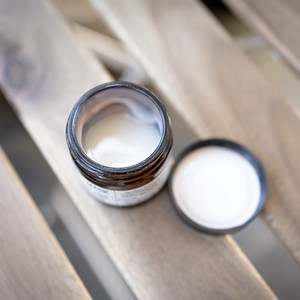 Pot de crème hydratante ouvert sur une table en bois