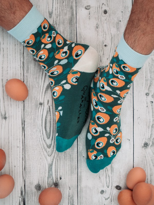 Pieds portant les chaussettes aux motifs mélengeant oranges et vertes; des œufs durs atour en décor
