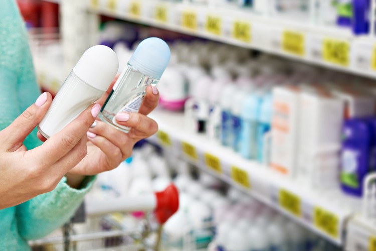 Une femme hésite entre deux déodorants au supermarché