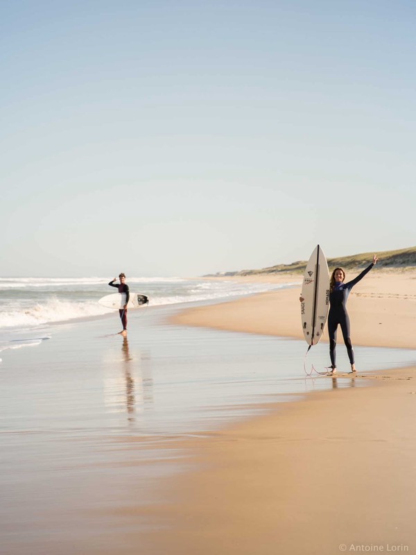 Une surfeuse et un surfeur sur une plage avec des planches Nomads Surfing