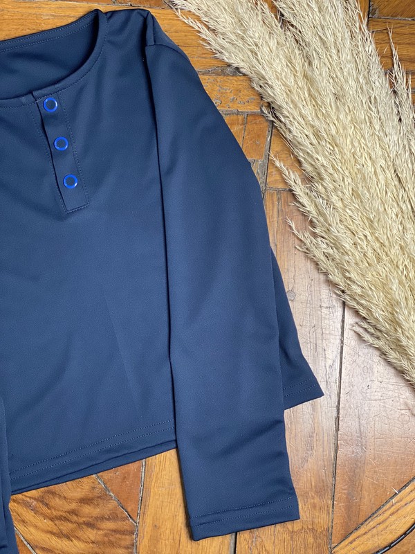 Deux tee-shirts anti-UV posés à côté d'une piscine (un blanc et un bleu marine)
